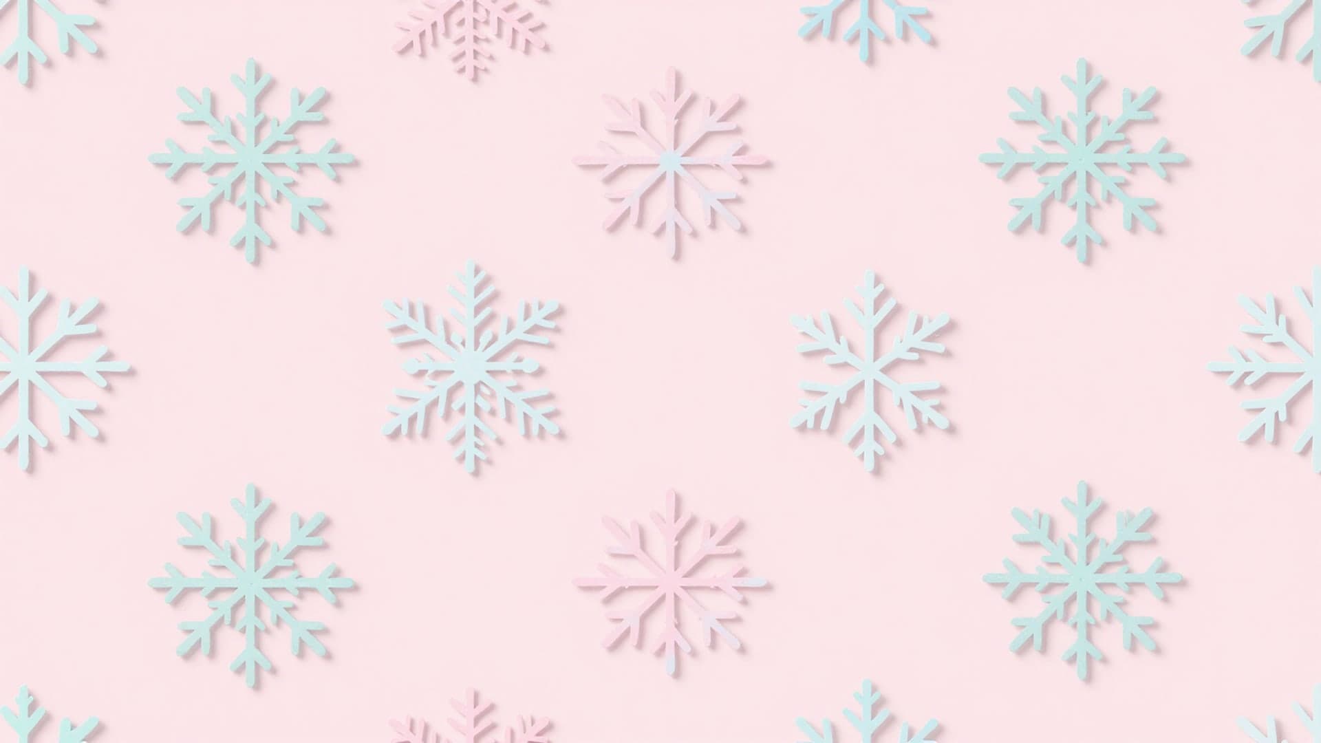 A repeating decorative pattern of pastel snowflakes arranged over a soft pink background.
